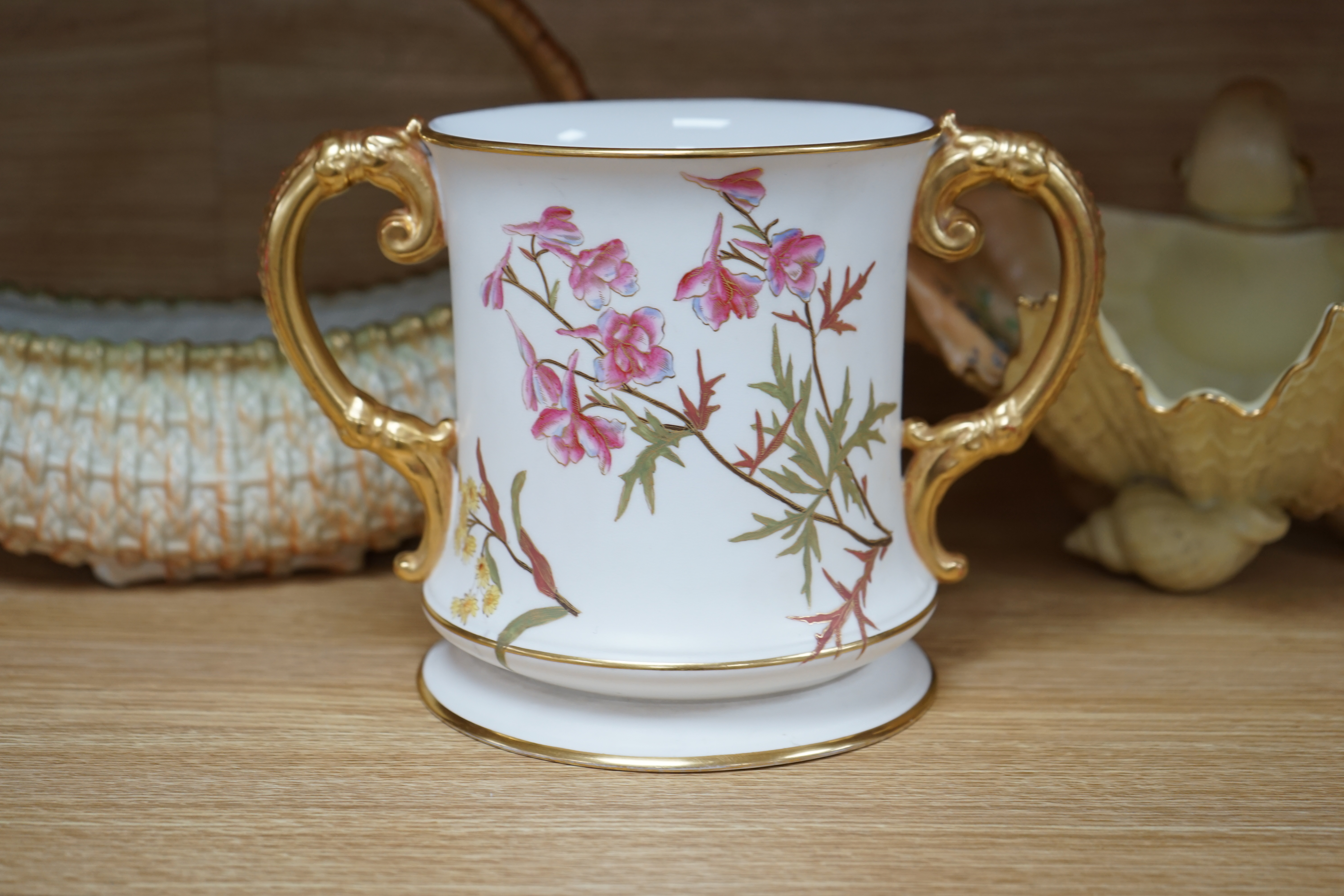 A Royal Worcester blush ivory basket, a shell dish and an ivory coloured two handled mug, 15.5cm (3). Condition - fair to good